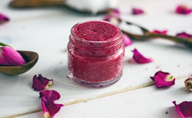 Homemade natural lip scrub from jojoba oil, cherry, rose oil and cane sugar in a small plastic jar....