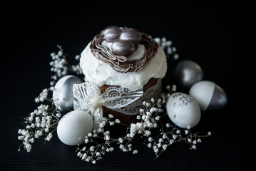 Traditional Easter cake with silver painted eggs on a black background. Selective focus