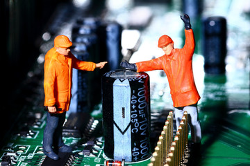 Conceptual diorama image of miniature figure workmen on an electronic circuit board