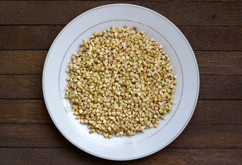 Sprouted buckwheat on white plate in center of wooden table