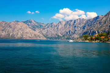 Incredible bright seascape. View of green wooded mountains and blue sea, blue sky and white clouds. Boka Kotorska Bay, Montenegro