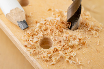 Drilling a hole in wood. Wood drill and plywood in a carpentry workshop.