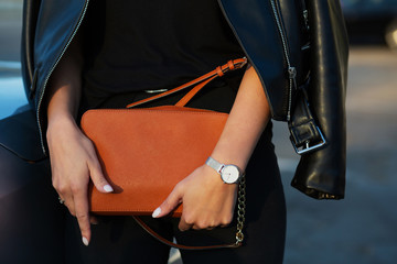 Luxurious young woman in black leather jacket holding orange purse - Powered by Adobe