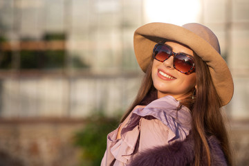 Street portrait of cheerful brunette model wears hat and sunglasses, enjoying warm weather. Empty space