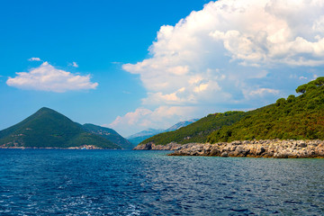 Incredible bright seascape. View of green wooded mountains and blue sea, blue sky and white clouds. Boka Kotorska Bay, Montenegro