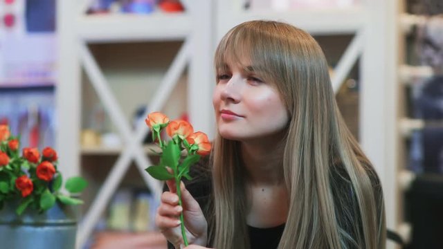 A young woman smelling a flower in a shop