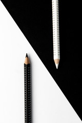 Two drawing pencils on a black and white surface.