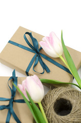 Kraft gift boxes with ribbons and tulips are on a white background