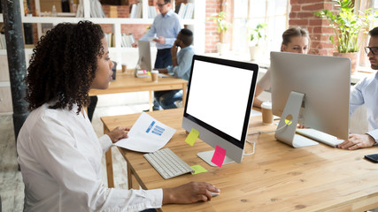 Black female employee sitting in coworking office working using laptop