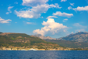 Fototapeta premium Incredible bright seascape. View of green wooded mountains and blue sea, blue sky and white clouds. Boka Kotorska Bay, Montenegro