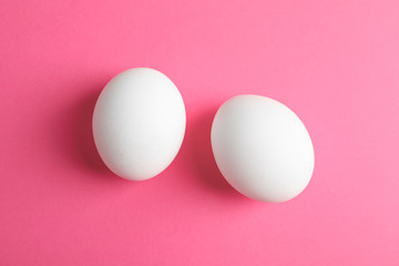 Chicken eggs on pink background, space for text