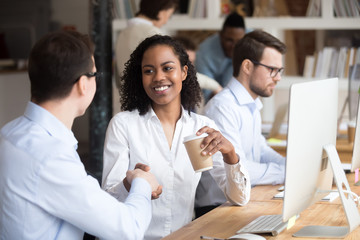 Diverse workers greeting each other shaking hands in coworking office