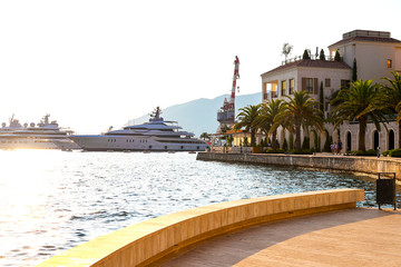 Scenic panoramic view of the historical city of Tivat, located in the Bay of Kotor on a sunny day at sunset in summer, the water reflects the rays of the sun, Montenegr