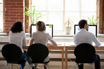 Women and man sitting in shared office rear back view