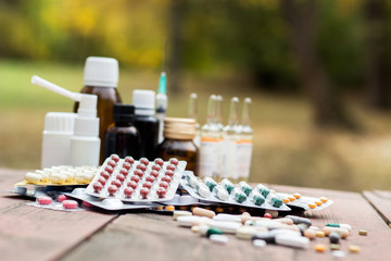 Medicines on wooden table, nature bokeh background