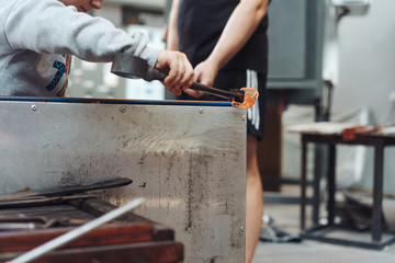 A glassblower student tries to make a flower out of glass