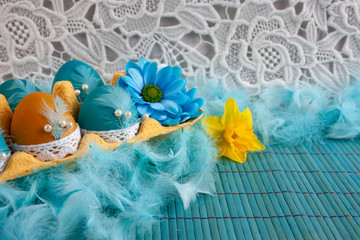 Wytłaczanka z niebieskimi i żółtymi pisankami, białą koronką i błękitnymi piórami © Monika