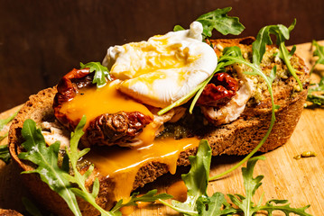 toast with dried tomatoes, poached egg and arugula leaves