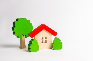 Wooden hut and tree figurines with bushes. The concept of a love nest. Country estate. Acquisition of affordable housing in a mortgage or loan. Accommodation for young families. Romantic gift.