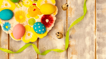 Easter background with Easter eggs and ribbons on a wooden white and gray table. Top view with copy space.
