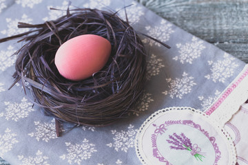 Easter decorations with Easter eggs in a decorative nest on the tablecloth handmade.