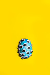 Blue egg shell is covered with googly eyes. Minimal concept