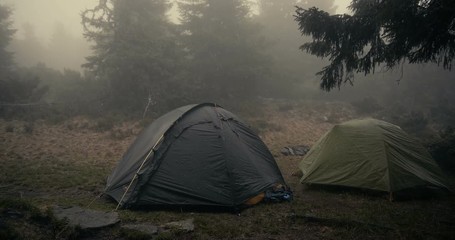 Two spherical tents under falling wet snow in Carpathians in autumn in slo-mo