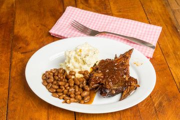 Beef Brisket Barbecue Dinner with Baked Beans and Potato Salad on Rustic Picnic Table