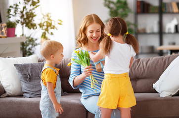 Happy mother's day! Children congratulates moms and gives her a gift and flowers .
