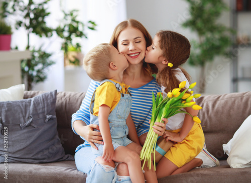 Happy mother's day! Children congratulates moms and gives her a gift and flowers .