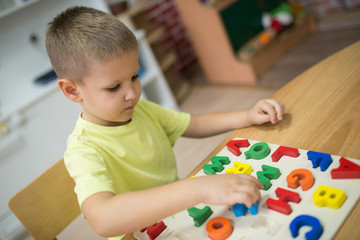 Little boy learning letters and shapes, play with puzzle
