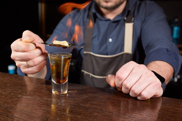 Fiery show at the bar. The bartender makes hot alcoholic cocktail and ignites bar. Bartender prepares a fiery cocktail. Fire on bar.