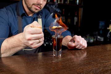 Fiery show at the bar. The bartender makes hot alcoholic cocktail and ignites bar. Bartender prepares a fiery cocktail. Fire on bar.