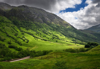 Fototapeta na wymiar Five Finger Gulley leading up to cloud covered Ben Nevis mountain and green slopes to River Nevis Scottish Highlands Scotland UK
