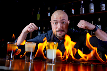 Fiery show at the bar. The bartender makes hot alcoholic cocktail and ignites bar. Bartender prepares a fiery cocktail. Fire on bar.