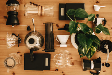 Alternative coffee brewing method set, flat lay. Stylish accessories and items for alternative coffee on wooden table. Kettle, scales, geyser, grinder, aeropress, pour over, glass flask top view