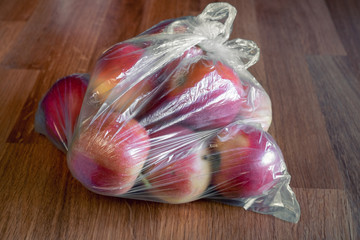 Apple fruit in plastic bag on wood table
