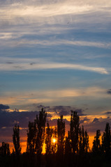 Landscape with dramatic light - beautiful golden sunset with saturated sky and clouds.