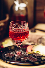 Glass of homemade redcurrant nalivka with apple slices and chocolate