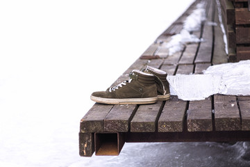 Men's shoes on the edge of a dock at the frozen river