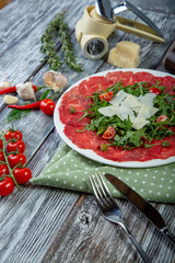 close-up carpaccio meat with arugula and slices of parmesan cheese