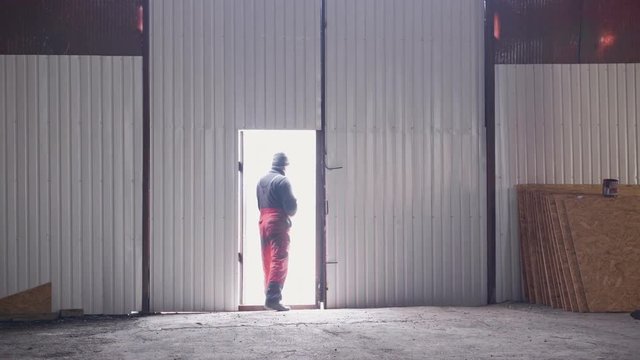 A worker comes out of a huge hangar where a bright light