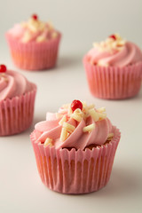 Close up pink, strawbery, fruit cupcakes isoalted. Sweet dessert, shortcakes with cream. Birthday food, cake, muffin. Tempalte for sugar addicted post for social media food content. Vertical image.
