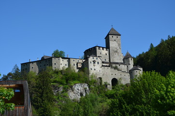Fototapeta na wymiar Burgruine auf einer Anhöhe mit Wald und blauem Himmel / Castle ruin on a hill with forest and blue sky