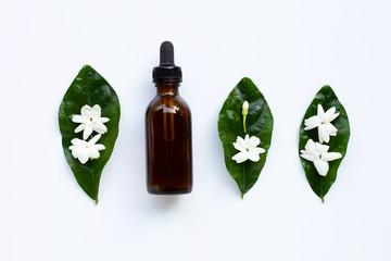 Bottle of essential oil with jasmine flower and leaves on white.