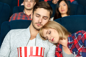 Bored to sleep. Closeup shot of a beautiful young couple sleeping during movies in a local cinema