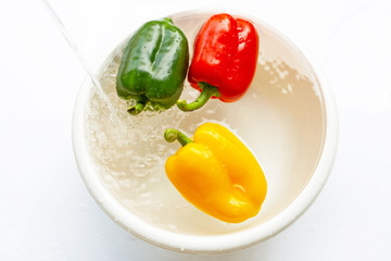 Bell pepper soaked in water. Washing fresh vegetables on white background.