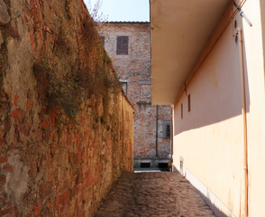 Ancient Italian cobblestone alley surrounded by weathered brick walls