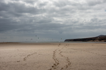 Sotavento Beach, Costa Calma, Fuerteventura, Canary Islands. Footprints on the sand. Kitesurfers and hills in the background. 