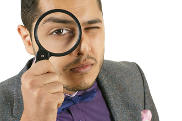 I see everything. Closeup studio portrait of a man looking to the camera through a magnifying glass